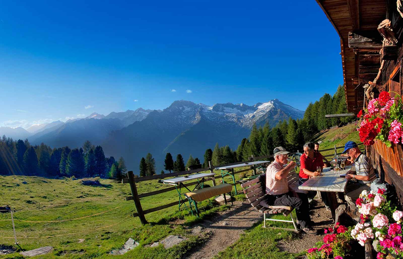 Eine Gruppe Wanderer trinkt ein Bier auf dem Berg mit einem wunderschönen Ausblick auf die umliegenden Berge.