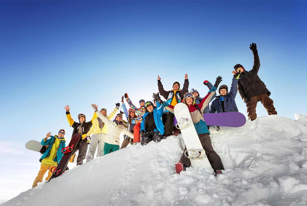Un gruppo di giovani con lo snowboard su una collina  innevata